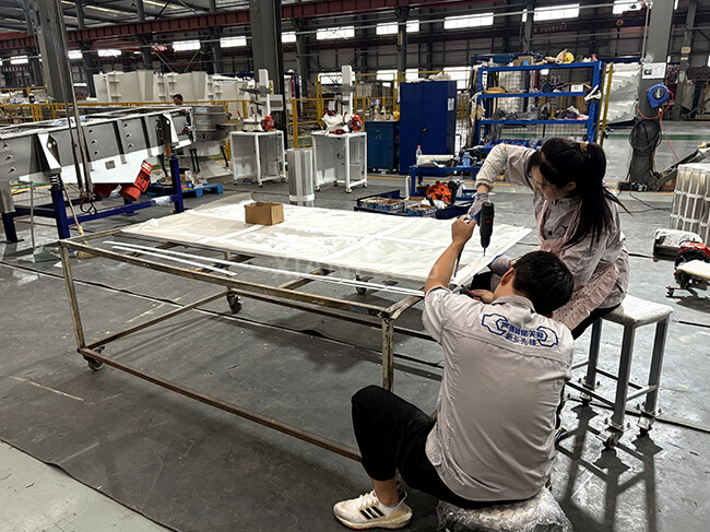 Worker Installing Vibrating Screen Mesh Real Shot - On-Site Installation of Wear-Resistant Screen for Sieving Machines
